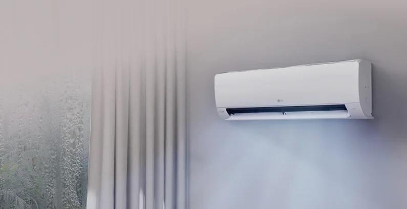 벽에 설치된 LG 휘센 벽걸이 에어컨이 보입니다. 에어컨은 흰색으로, 벽에 고정되어 있으며 아래쪽에서 시원한 바람이 나오는 모습입니다. 오른쪽에는 커튼이 드리워진 창문이 있습니다.