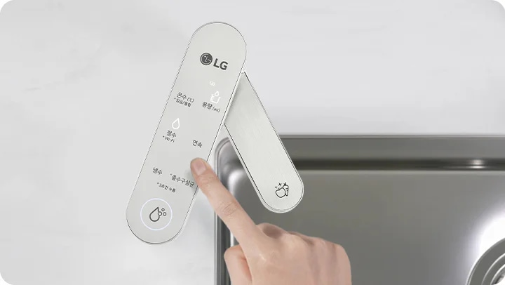 손가락이 금속 패널을 가리키고 있으며, 패널에는 온수, 냉수, 정수, 정수+냉수, 정수+온수라는 텍스트와 아이콘이 표시되어 있습니다. 패널은 세면대 옆에 위치해 있습니다.